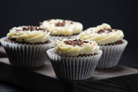 Chocolate cupcakes with creamcheese frosting on wooden cutting boardの写真素材