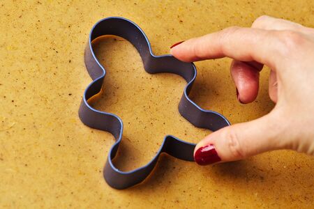 Female hand making christmas gingerbread men cookies with metal cutterの写真素材