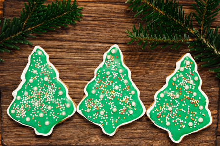 Gingerbread Christmas tree cookies with fir's branch on the wooden backgroundの写真素材