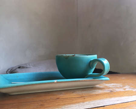 Relaxing time, a blue cup of coffee on the rustic wooden table with grey wall background