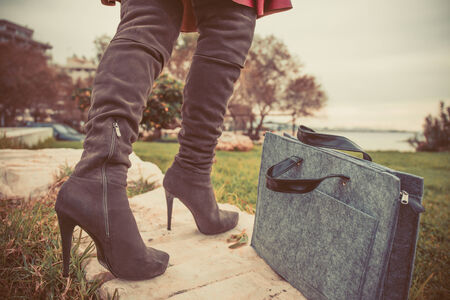 woman legs wearing boots and hand bagの写真素材