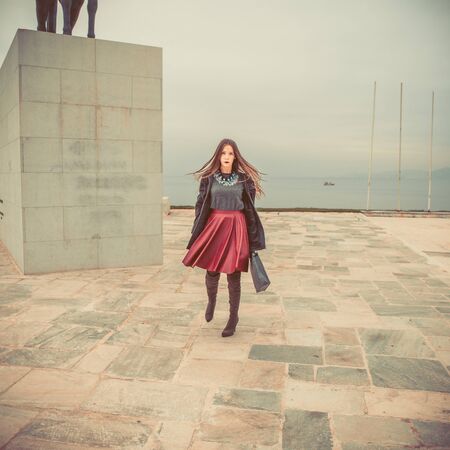 young woman dressed in skirt and blouse posing on streetの写真素材