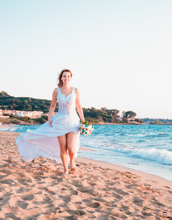 bride walking on a beach on sunsetの写真素材