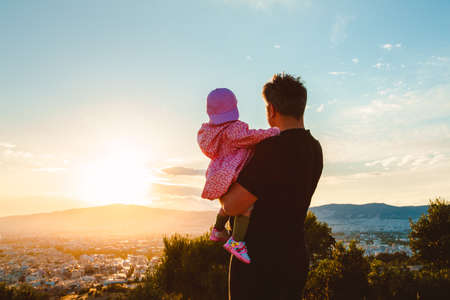 father holding his baby and looking to the sunsetの写真素材