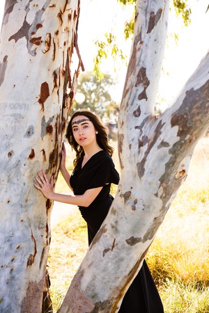 portrait of young lady in black dress near the treeの写真素材