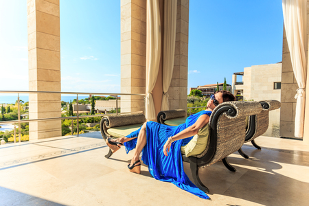 young lady in blue dress laying on a sofaの写真素材