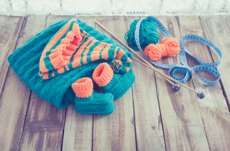 knitted green and orange childrens set on wooden tableの写真素材