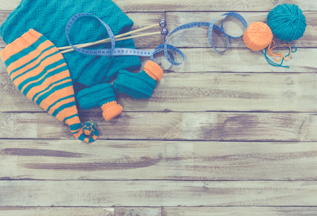 knitted green and orange childrens set on wooden tableの写真素材