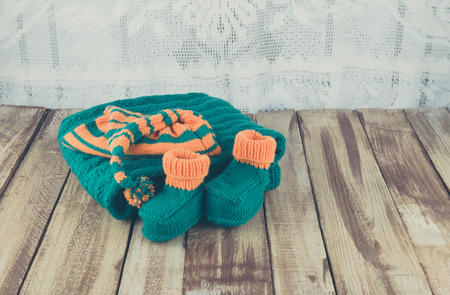 knitted green and orange childrens set on wooden tableの写真素材