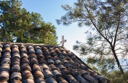 white stone cross on a tile roofの写真素材