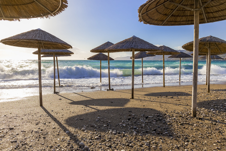 Umbreles on the sand beach with cloudy blue sky and sunの写真素材