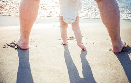 Close up of father and little daughter feet on beachの写真素材