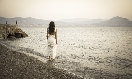 Girl standing on the beach with white dress retro photoの写真素材