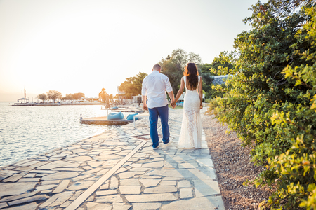 back view of happy young couple in white on the prominadeの写真素材