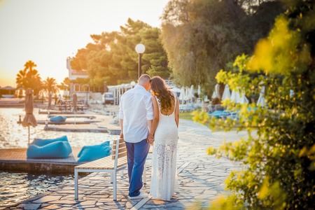 back view of happy young couple in white on the prominadeの写真素材