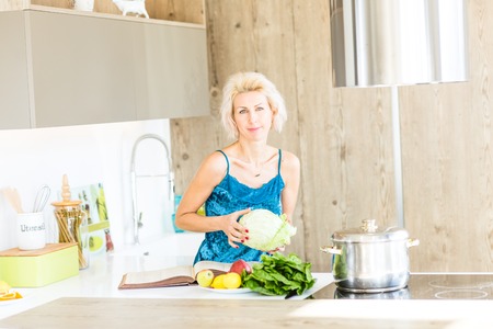 young blonde woman cooking in modern kitchenの写真素材