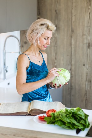 young blonde woman cooking in modern kitchenの写真素材