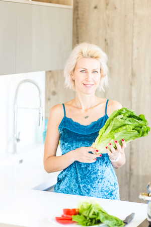 young blonde woman cooking in modern kitchenの写真素材