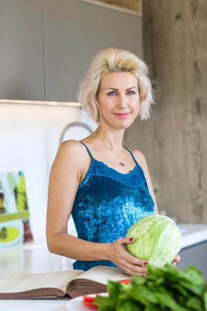 young blonde woman cooking in modern kitchenの写真素材