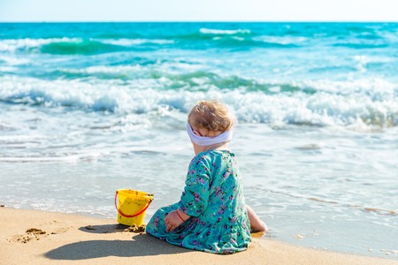 Cute baby girl playing with beach toys on tropical beachの写真素材