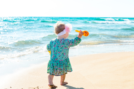 Cute baby girl playing with beach toys on tropical beachの写真素材