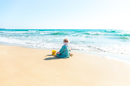 Cute baby girl playing with beach toys on tropical beachの写真素材