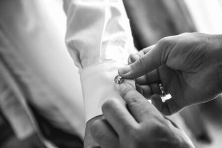 helps groom to put on cufflinks close upの写真素材
