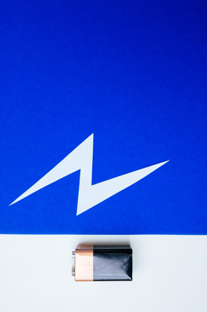 Damaged battery resting on textured blue surface with taped contactsの写真素材