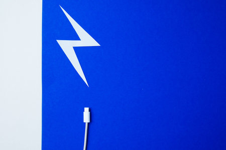 Detailed View Of Lightning Icon On Cable Tip Set Against Bright Blue Backdrop For Contemporary Styleの写真素材