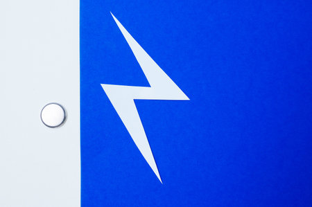 Tiny Blue Power Button Cell With Shiny Metal Edges Symbolizing Electronic Energy Flowの写真素材