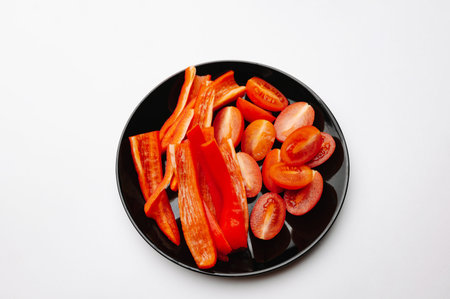 Photograph Showcasing Sliced Red Peppers And Tomatoes On Dark Surface For Healthy Eating Inspirationの写真素材