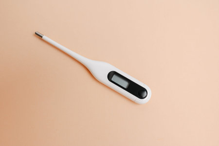 Minimalist White Digital Thermometer Featuring Metal Tip Against Peach Background For Health Checks