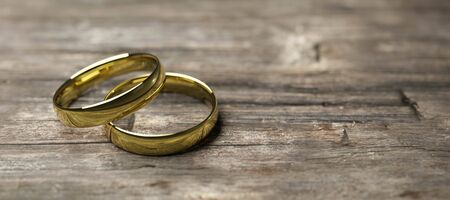 Two golden wedding rings on wooden table soft focus macro shot as a symbol of marriage or connection