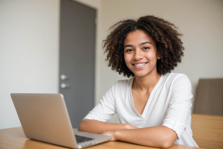 Smiling Young Woman Working on Laptop at Deskの素材