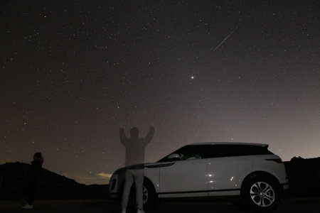 Night view of the starry sky with a silhouette of a man and his carの写真素材