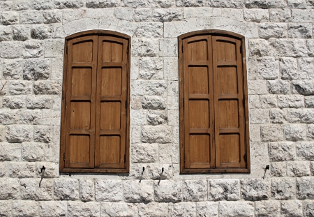 A limestone wall with two closed windows.の写真素材