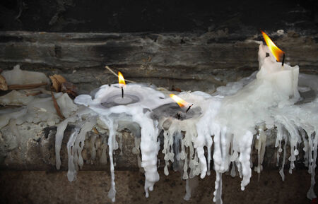 Three lit candles burning and melting の写真素材