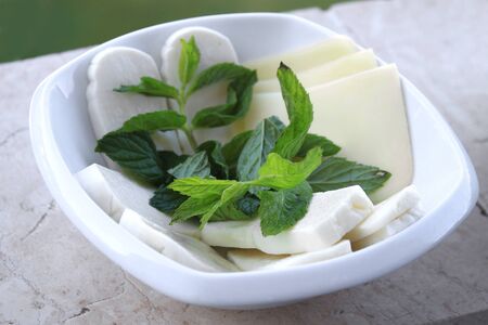 A selection of cheese with mint in a white plate.の写真素材