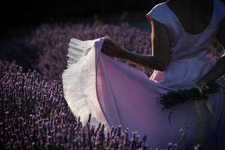 A woman in a pink dress with ruffles dancing in a lavender field.の写真素材