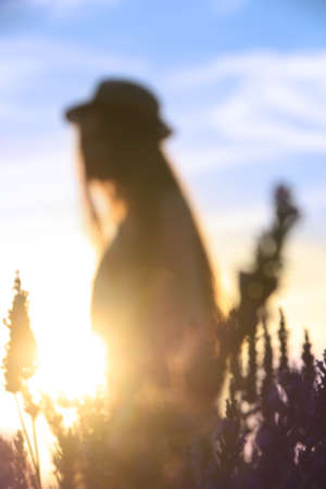 A girl with a hat on in a lavender field, out-of-focus scene.の写真素材