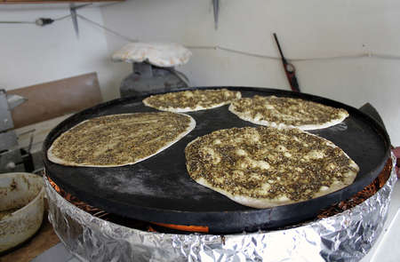Four manaqeesh being baked on a saj oven, the mankousheh is a famous Lebanese breakfast.