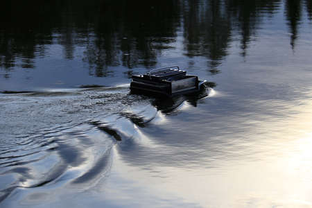 A remote controlled feeder boat in a lake used in recreational fishing.