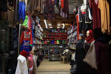 A clothing stall with various garments and headscarves in an old souk in Tripoli, Lebanon.