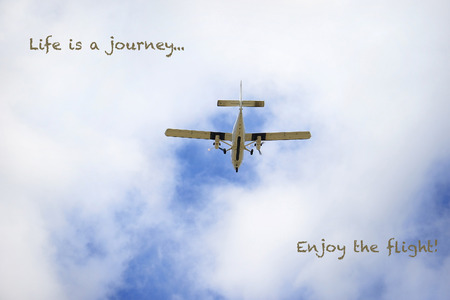 An old propeller airplane flying in a cloudy sky.