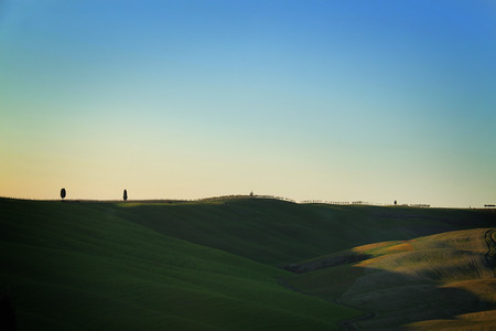 Rolling hills of Tuscany and cypress trees in the distance.の写真素材
