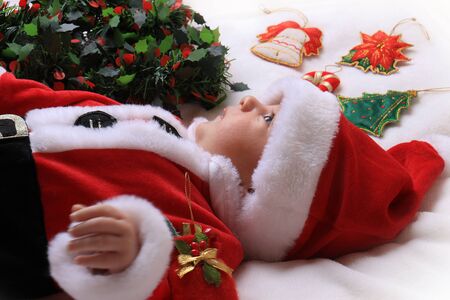 A newborn in Santa Claus outfit amongst Christmas decorations.の写真素材