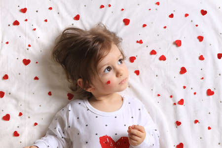 A toddler with lots of red hearts surrounding him on white.の写真素材