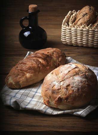 Loaves of bread and a balsamic vinegar bottle in a rustic setting.