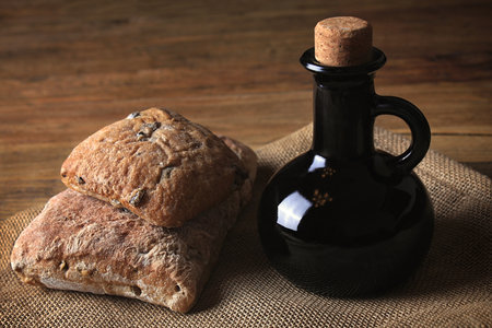 Two loaves of bread and a bottle of balsamic vinegar in a rustic setting.