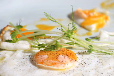 Fried sunny side up eggs with green garnish and black pepper.
